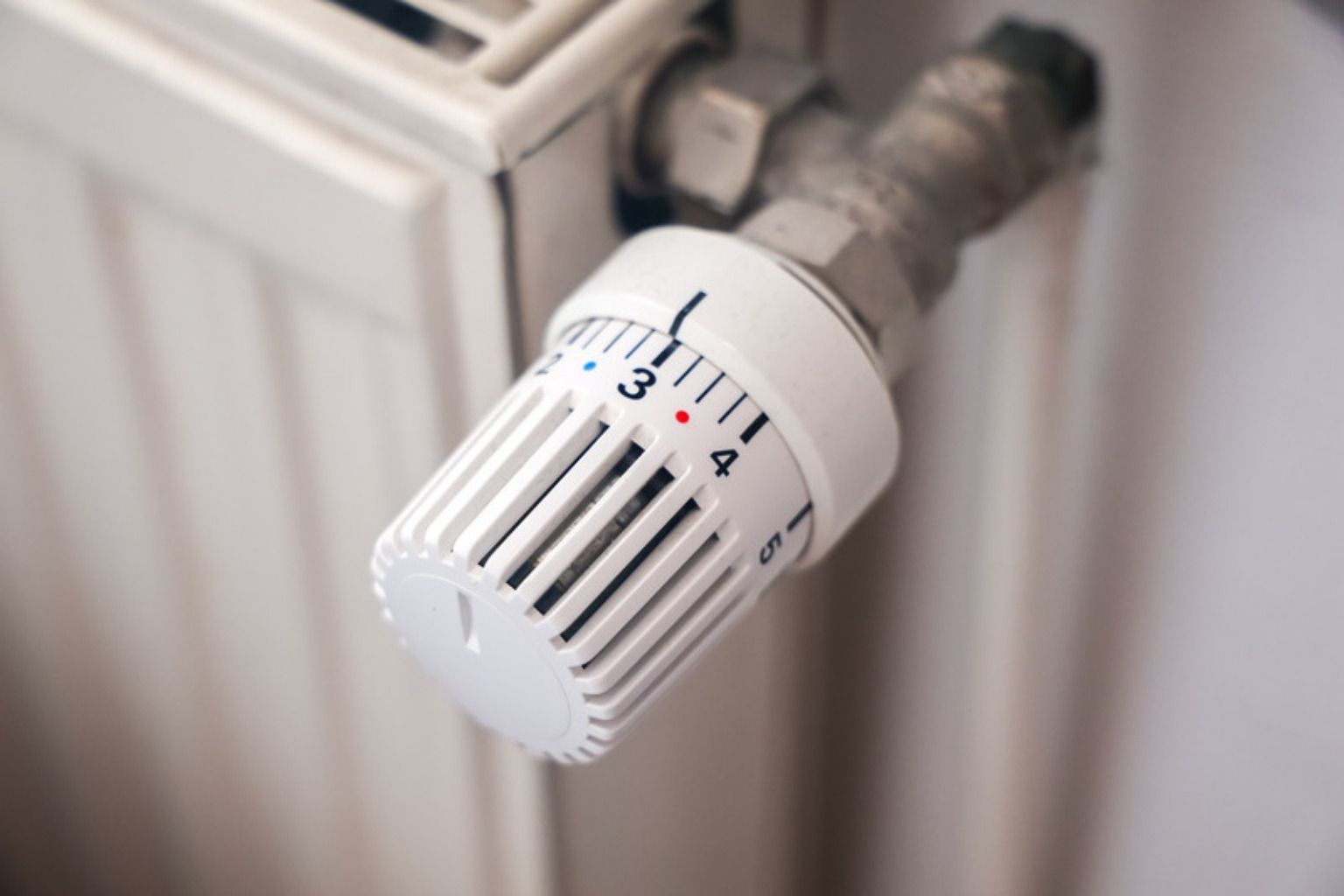 Nærbillede af et hvidt termostathoved med talskala på en radiatorventil